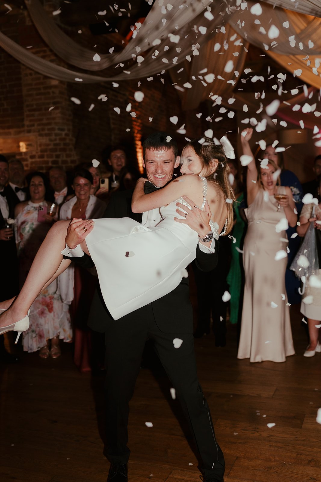 Confetti throw and the groom carrying the bride at the end of the evening party for the wedding of Becky + Harley, coordinated by Hardesty Event Design