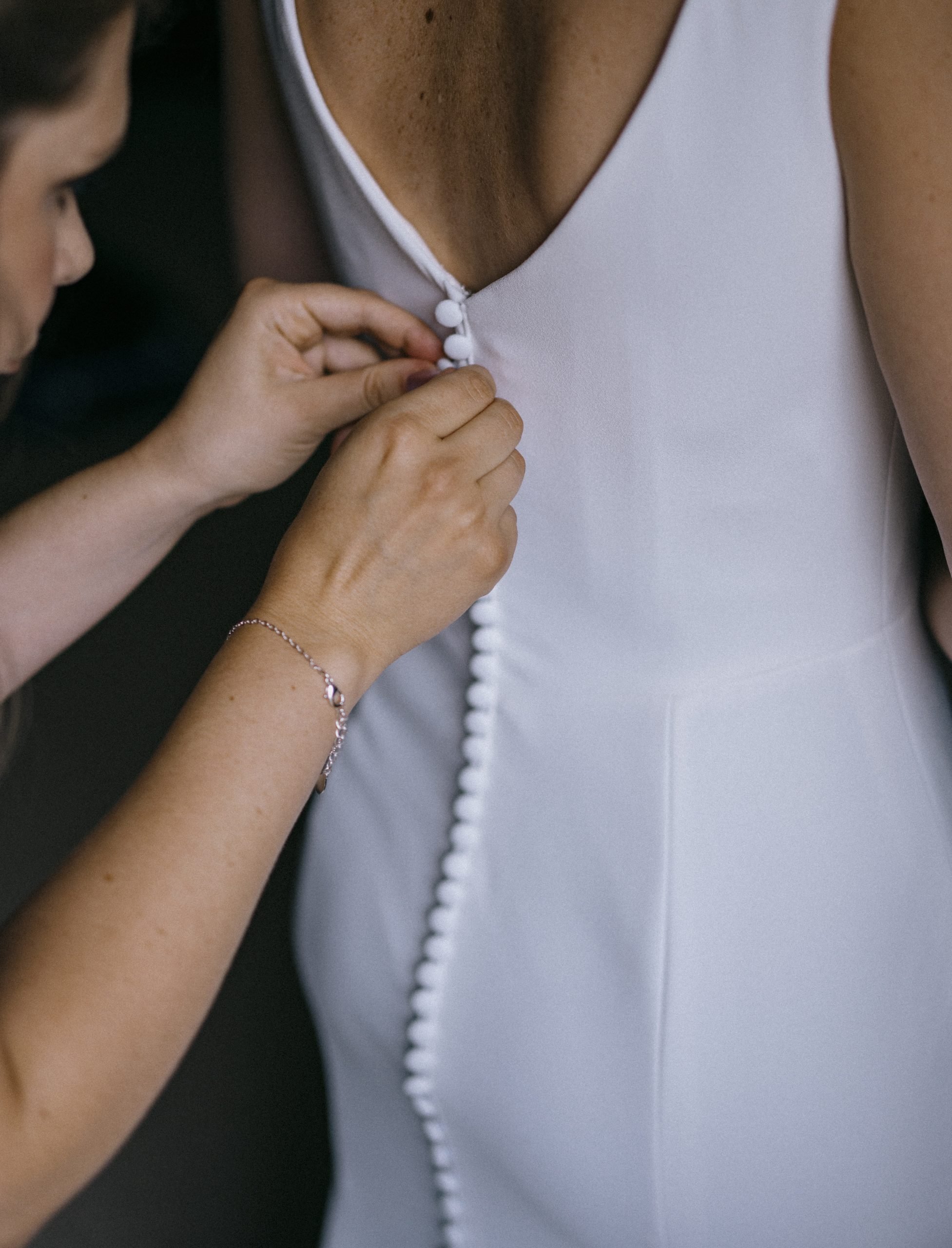 Bride having wedding dress buttoned at Worstead Estate