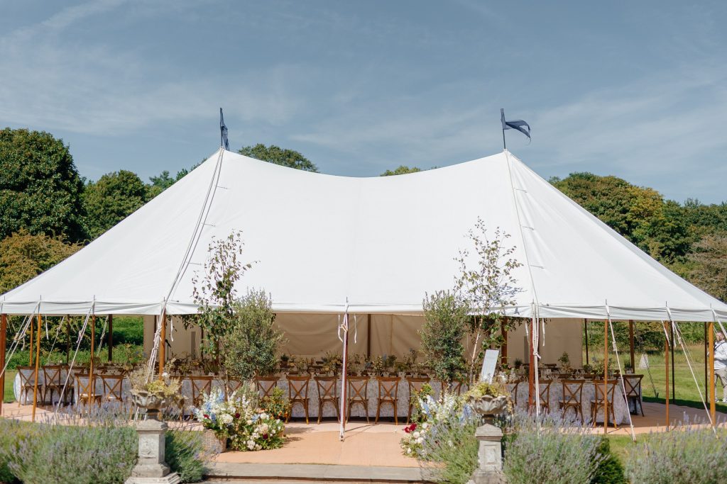 a close up shot of a marquee in the grounds of Butley Priory in Suffolk showcasing the beautiful work by the Hardesty Event Design team with a collection of potted trees and flowers at the entrance