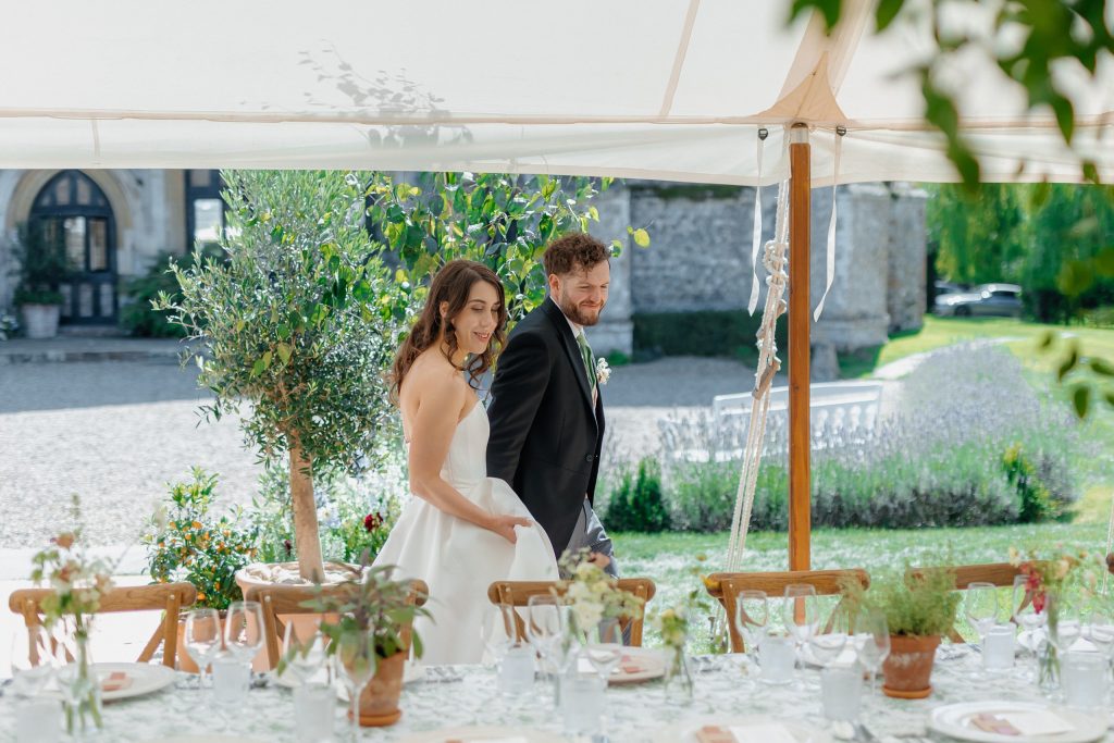 a bride and groom admiring the work of their wedding planner's team designing and creating a tablescape for their wedding day at Butley Priory in Suffolk