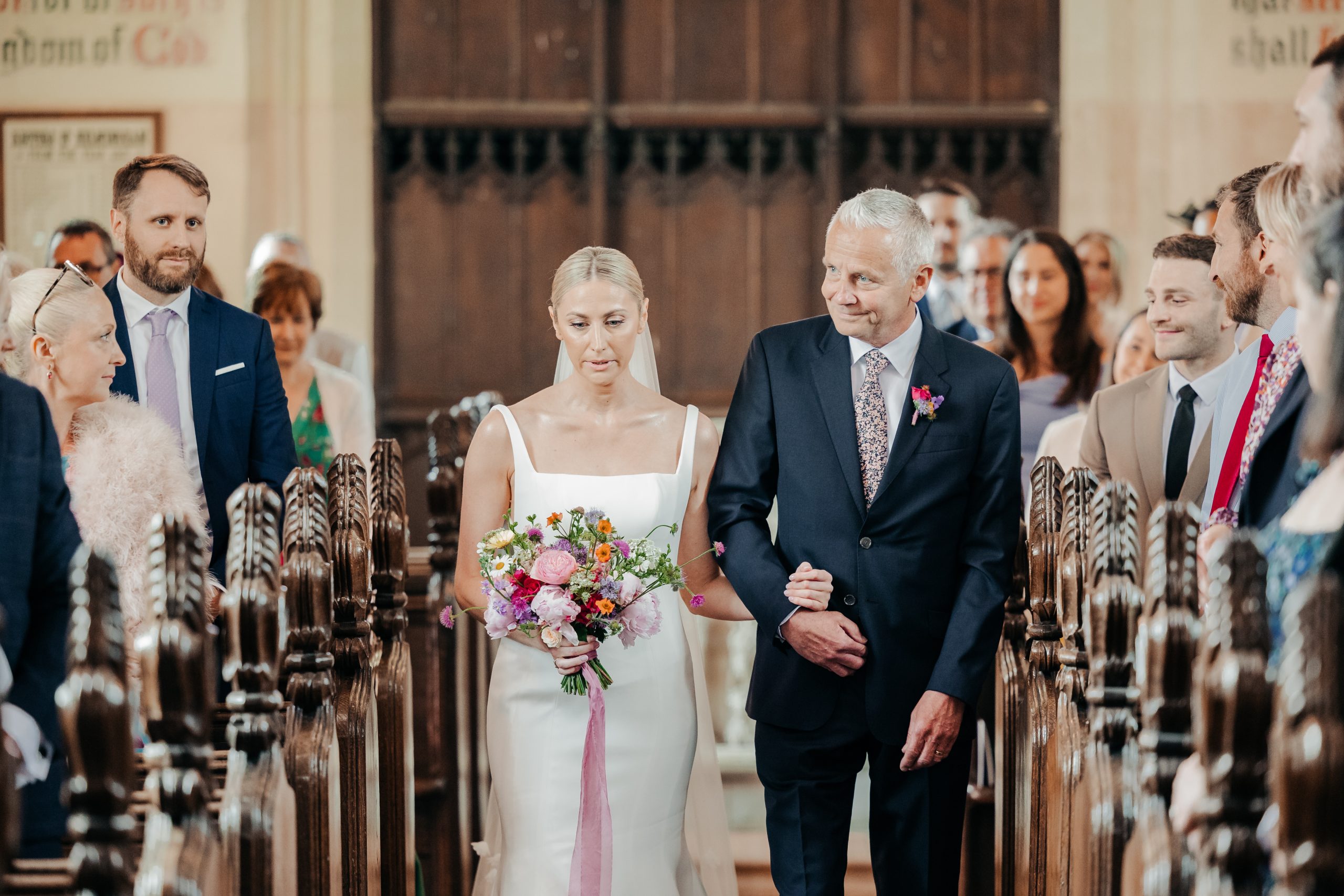 Bride and father of the bride walking up the aisle in church ahead of their luxury marquee wedding held in the grounds of Helmingham Hall, coordinated by Hardesty Event Design