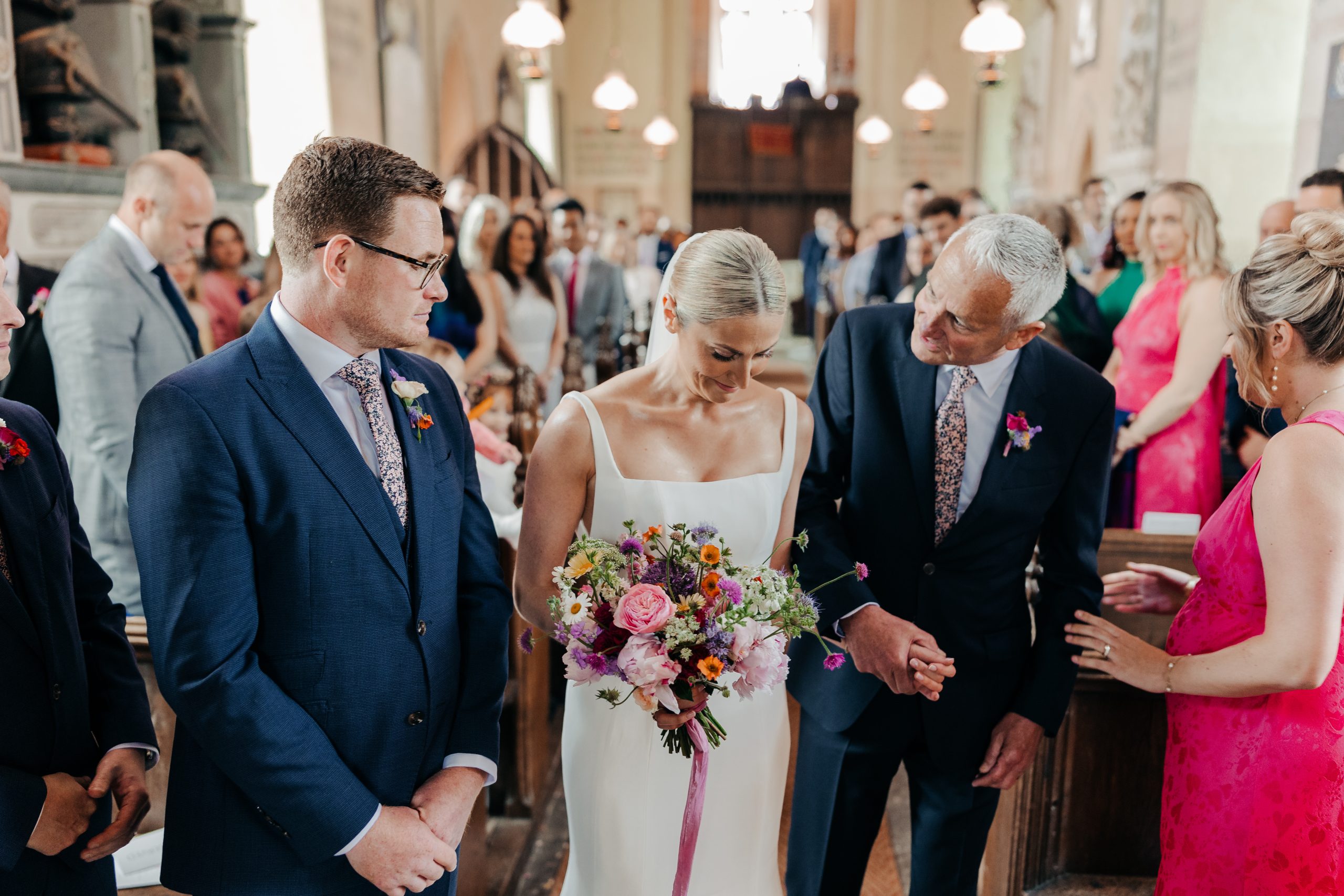 Bride and father of the bride walking up the aisle in church ahead of their luxury marquee wedding held in the grounds of Helmingham Hall, coordinated by Hardesty Event Design