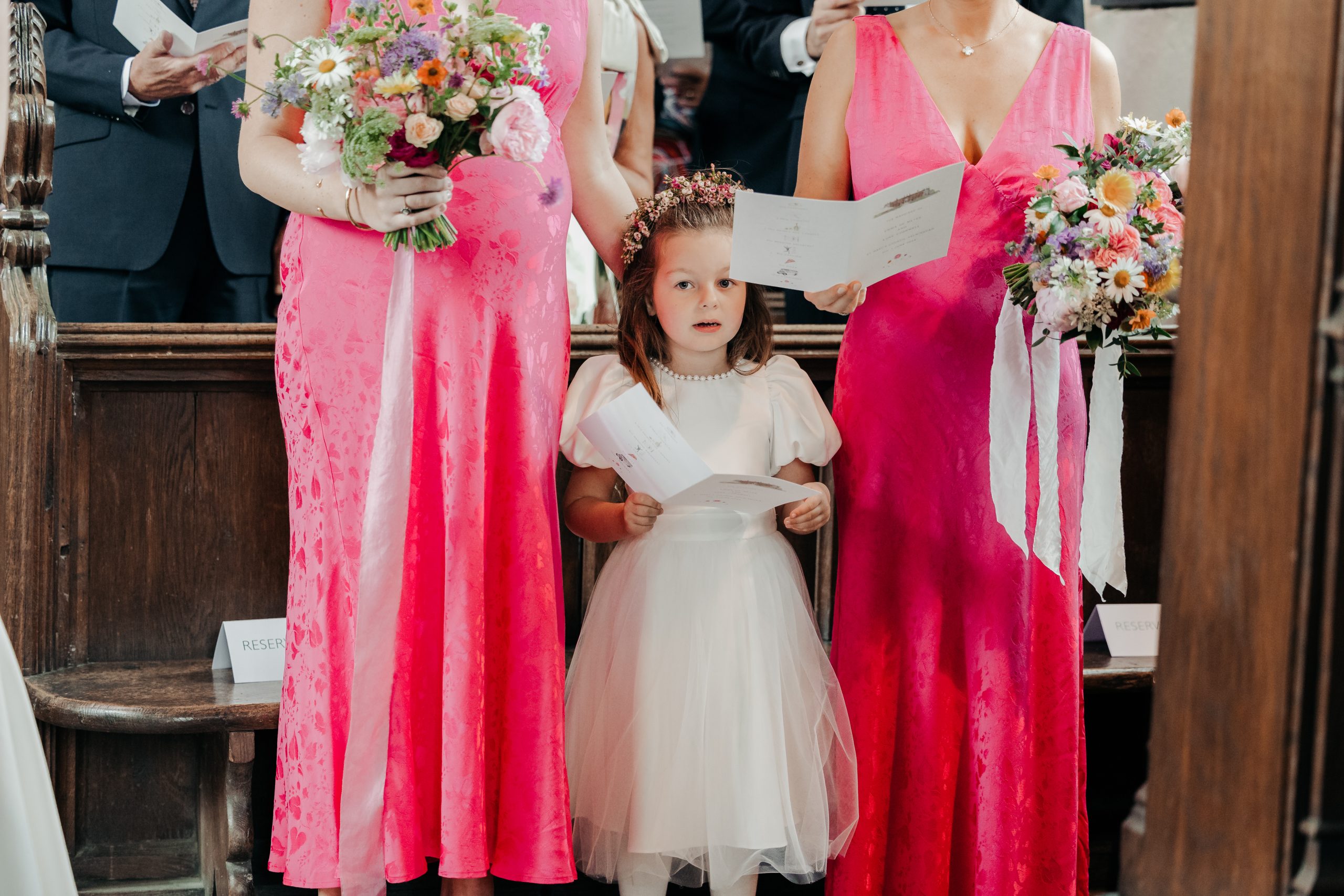 bridesmaids and flower girls singing in church during Emma and Luke's church service, coordinated by expert wedding coordinators in the UK