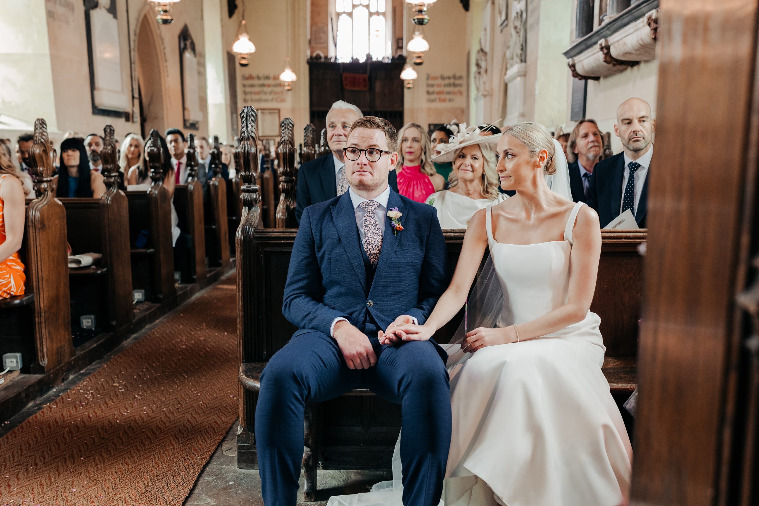 bride and groom sat during church service on their wedding day, planned by expert wedding planners in UK