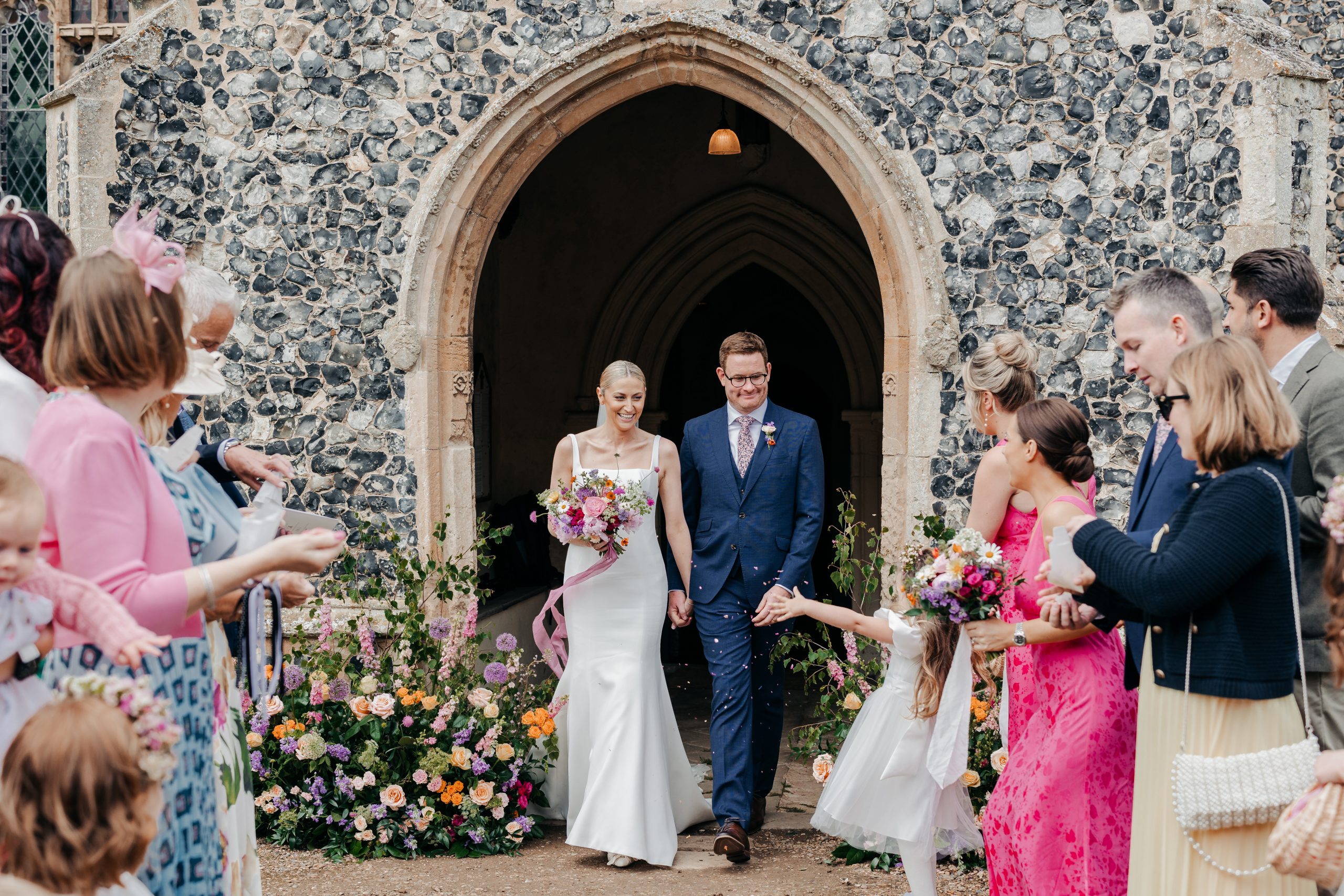 Bride and groom leaving church at a country house wedding in Norfolk, captured at a luxury wedding weekend event