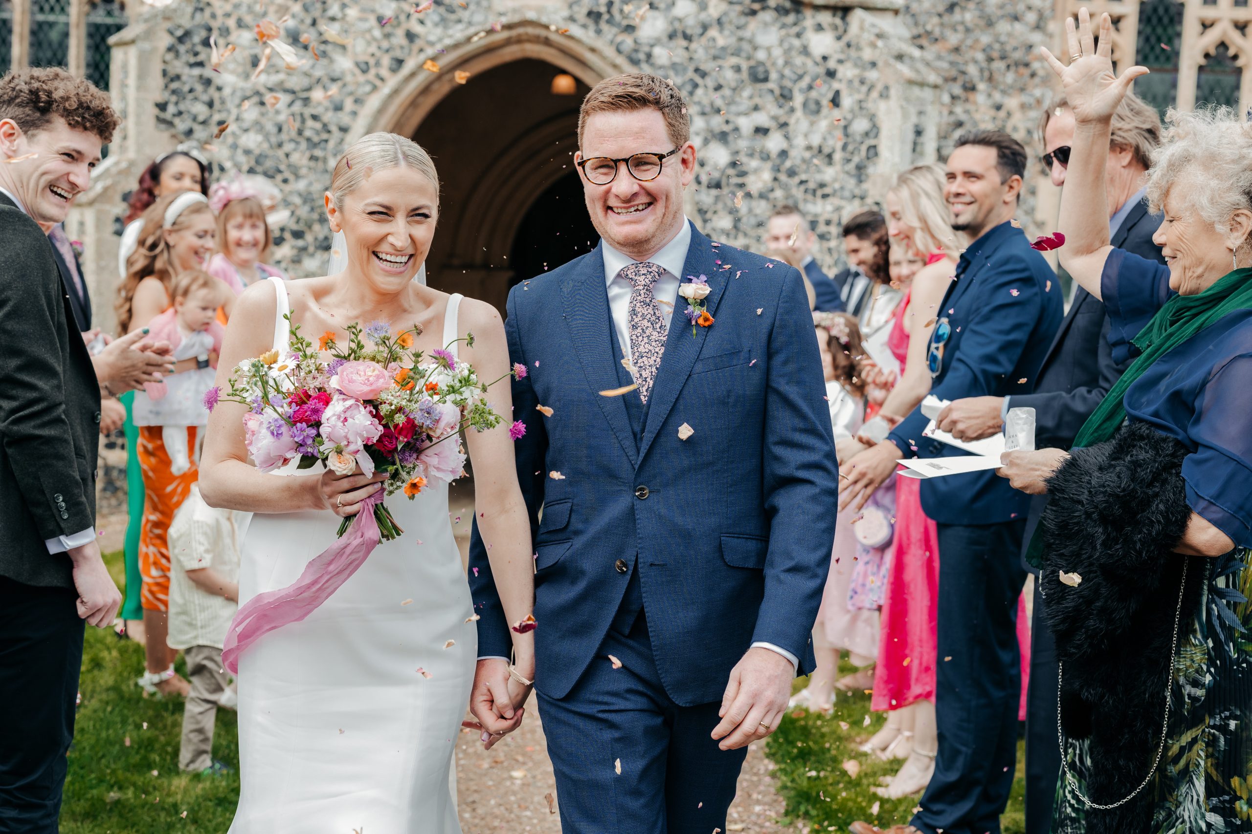 Emma & Luke sharing a moment during confetti outside their church, styled by a high-end UK wedding planner