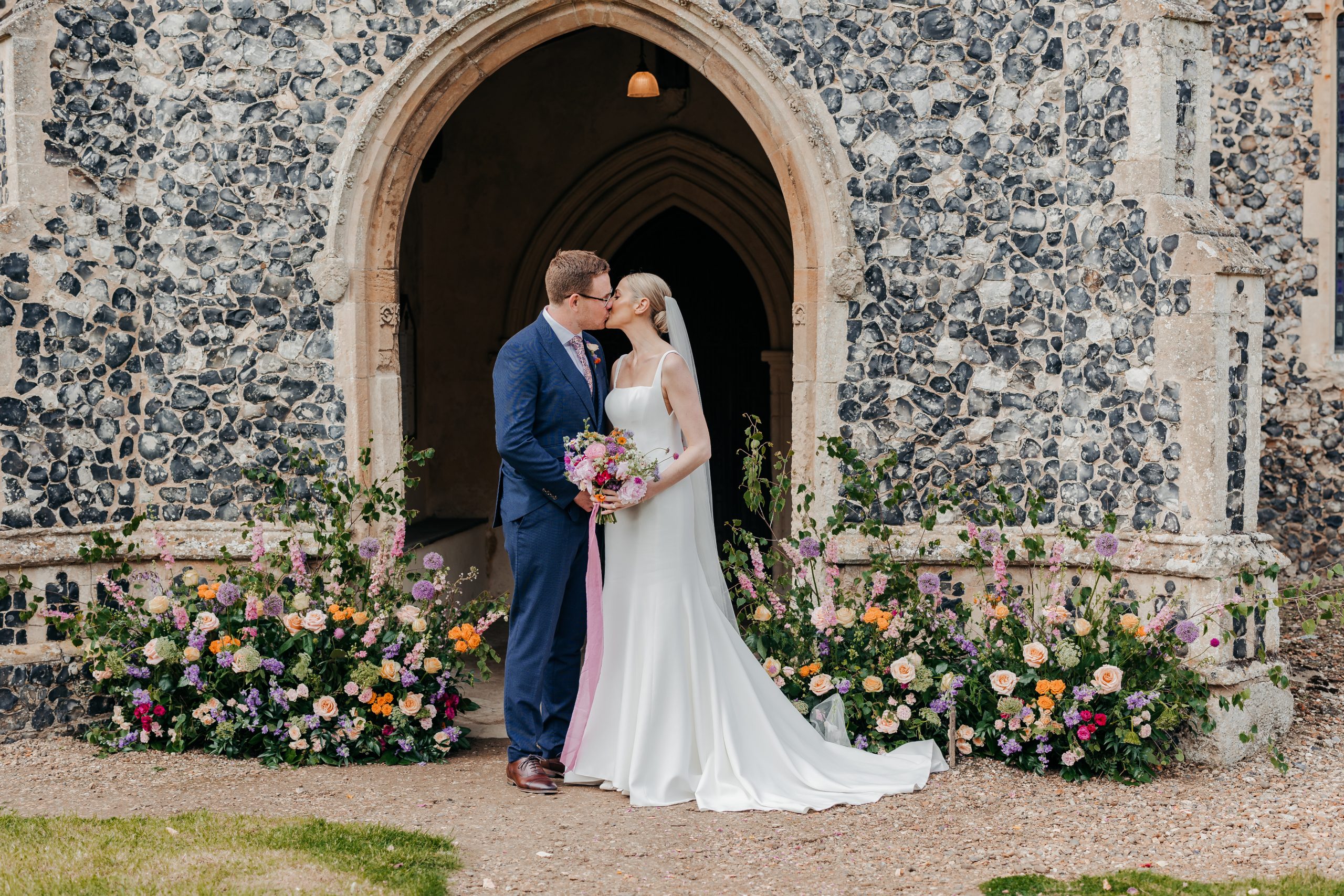 bride and groom exchanging a kiss outside the church on their wedding day in suffolk, planned professionally by Hardesty Event Design