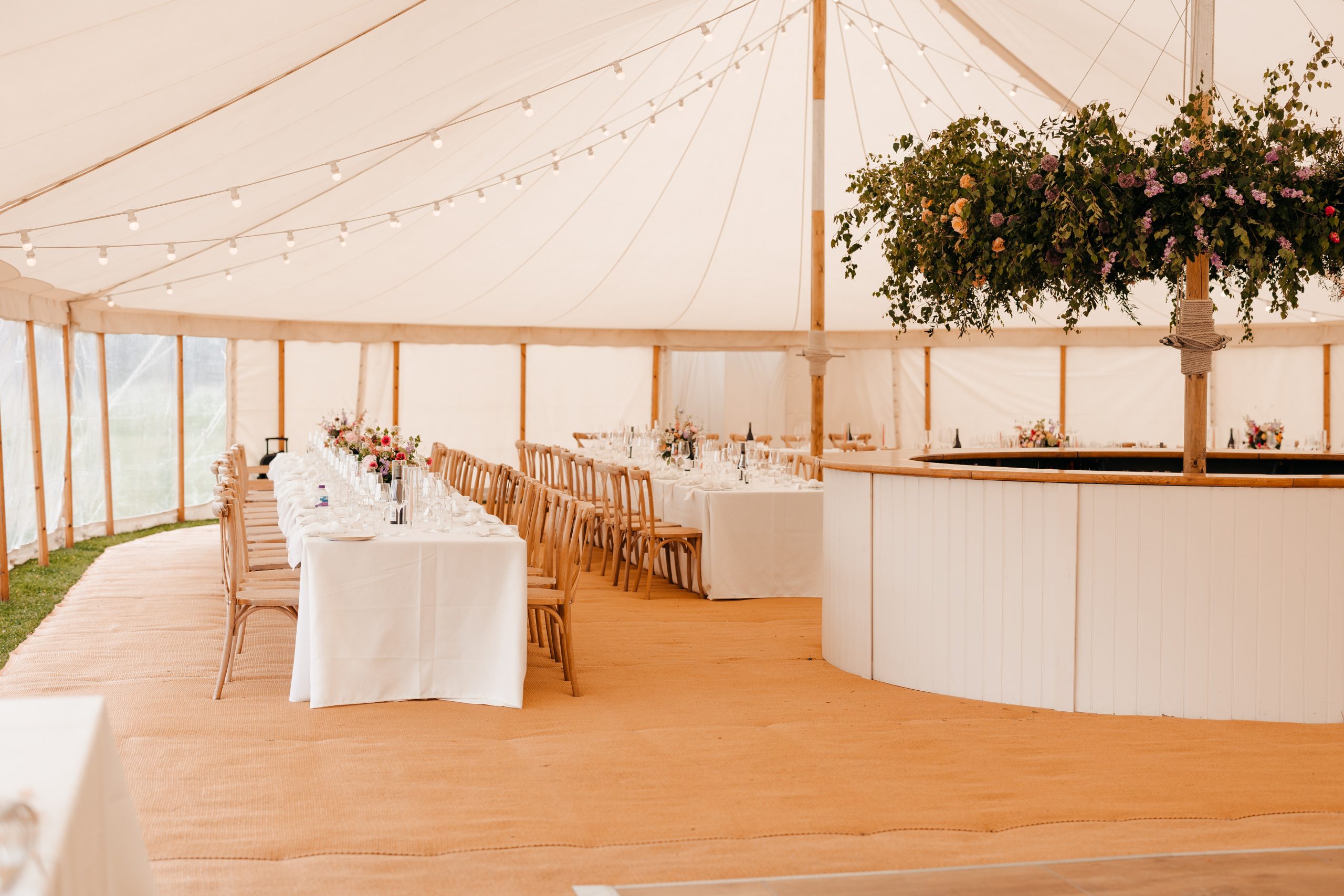 Refined tablescape in a beautiful sail cloth marquee at Helmingham Hall with cream linens and floral centrepieces, styled by uk wedding planner Hardesty Event Design