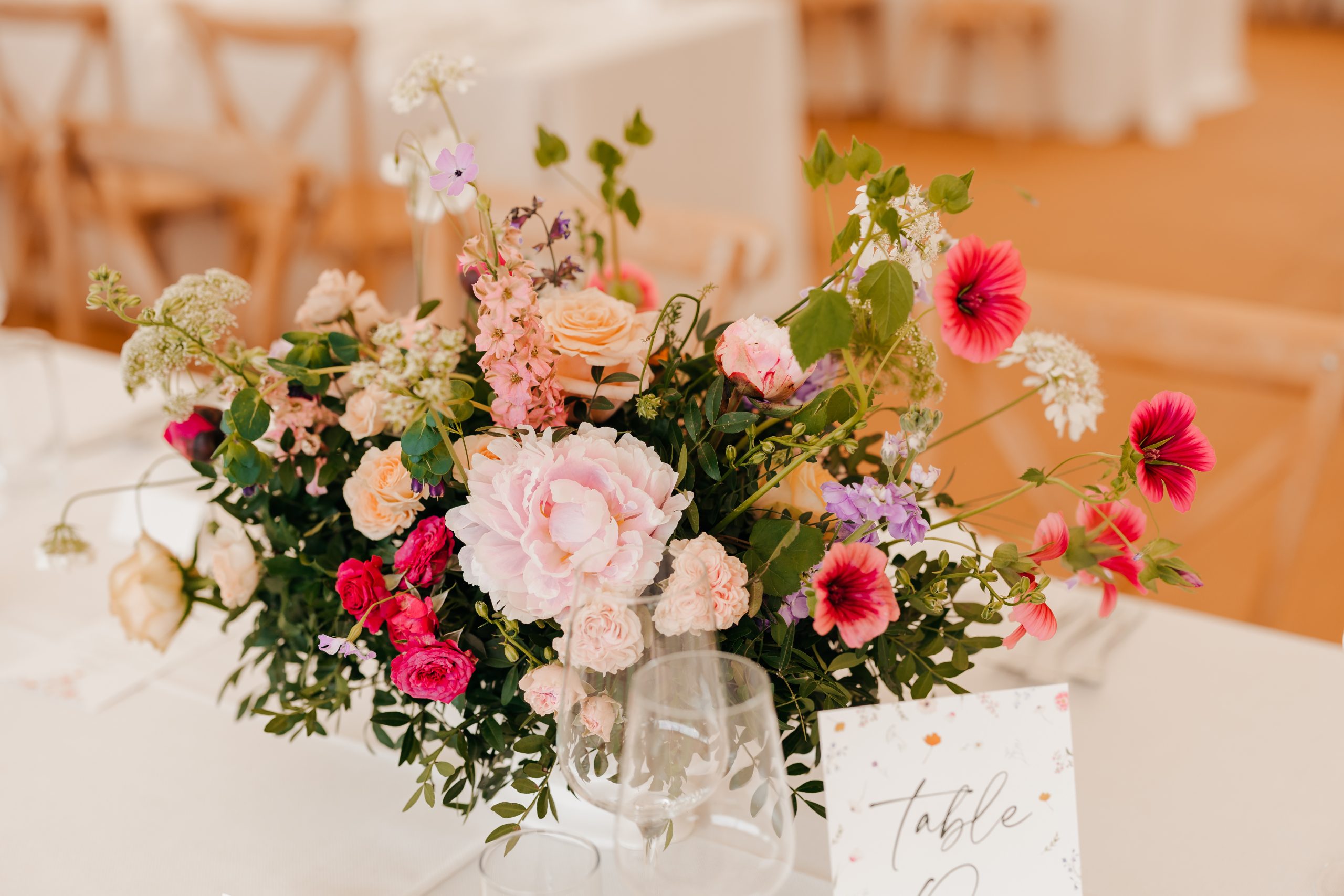 Close up of bright colourful wedding flowers on the tables in a marquee at Helmingham Hall, suffolk