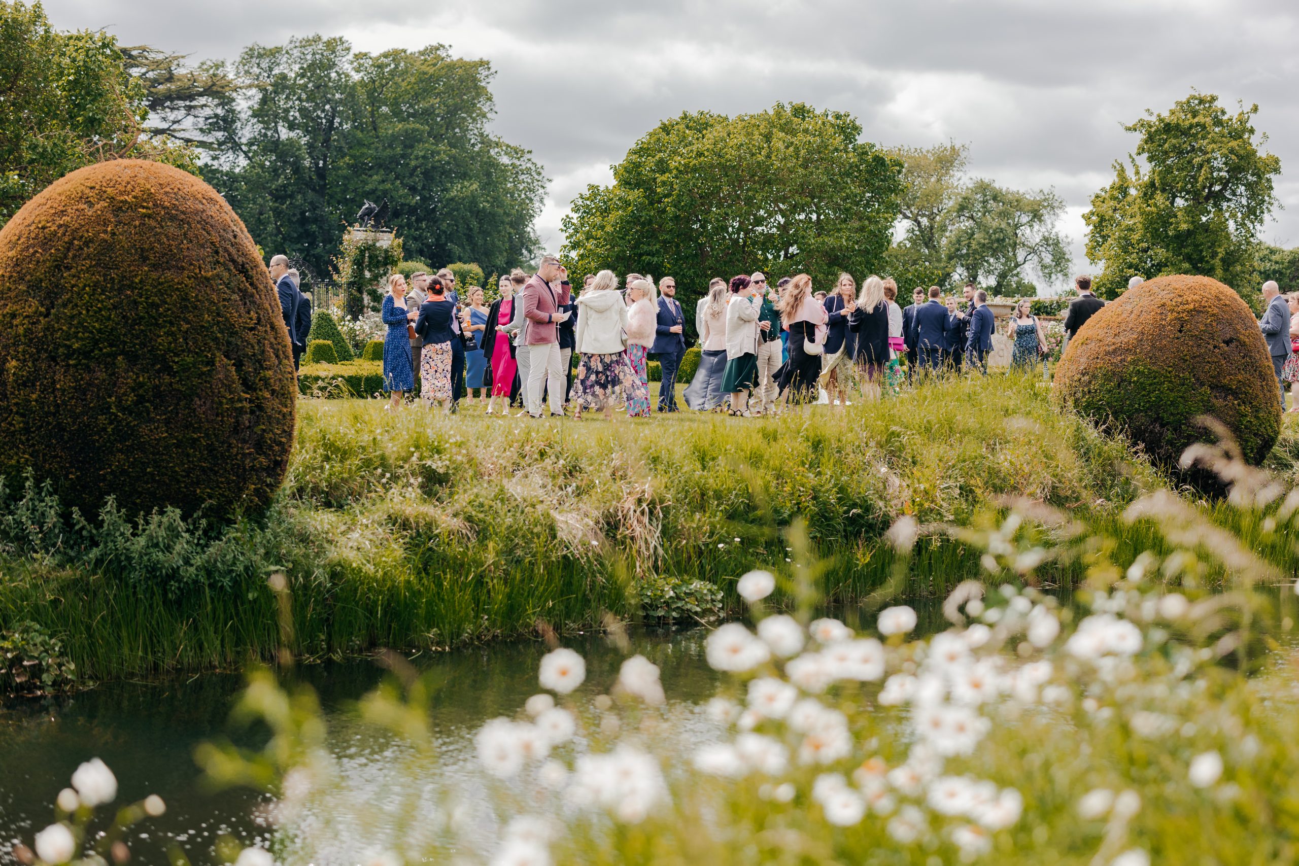 wedding guests in the grounds of Helmingham Hall, Suffolk for a wedding professionally planned by Uk wedding planner Hardesty Event Design