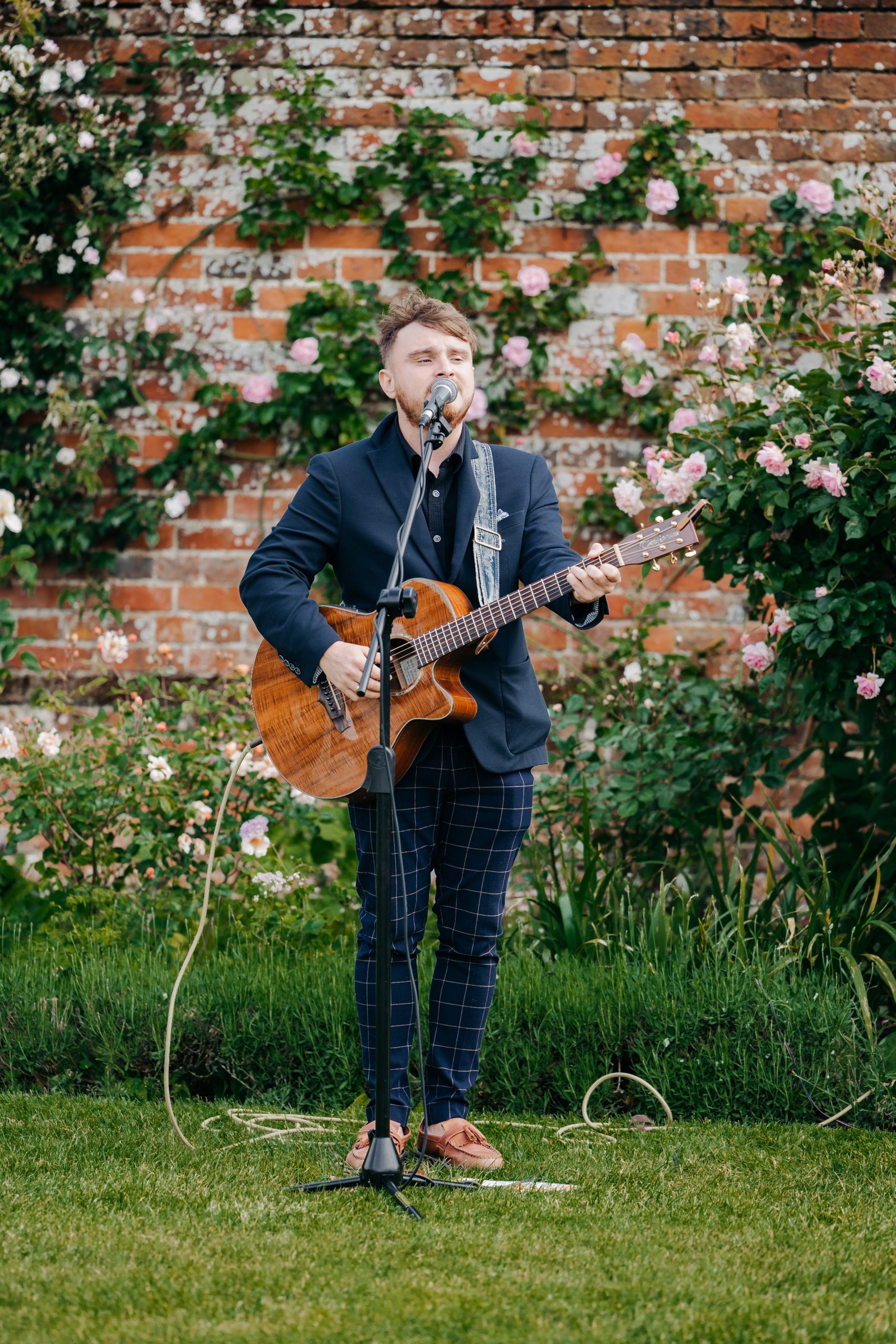 Acoustic wedding singer serending wedding guests in the grounds of Helmingham Hall, Suffolk