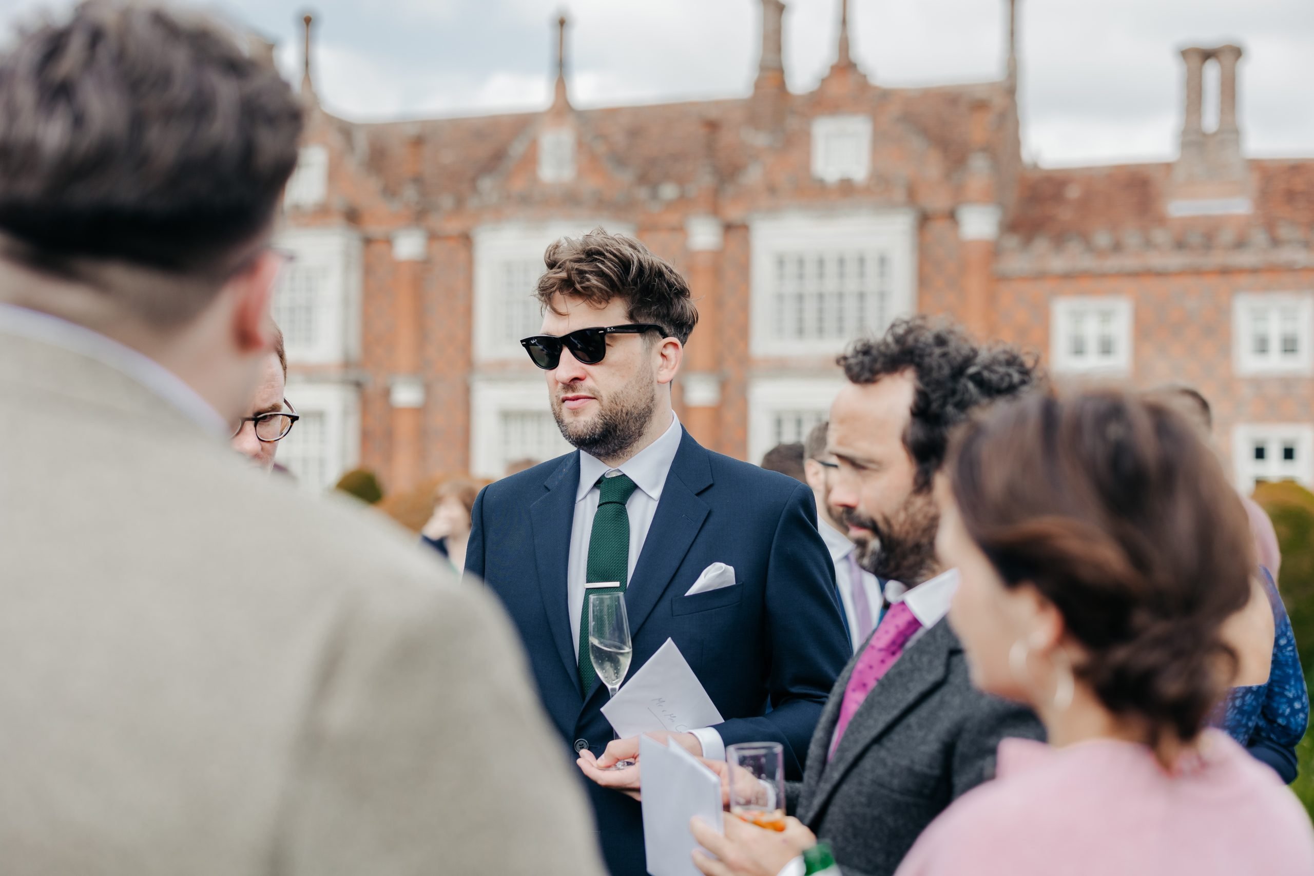 Wedding guests enjoying a champagne reception at a marquee wedding in Suffolk, planned by UK wedding planners