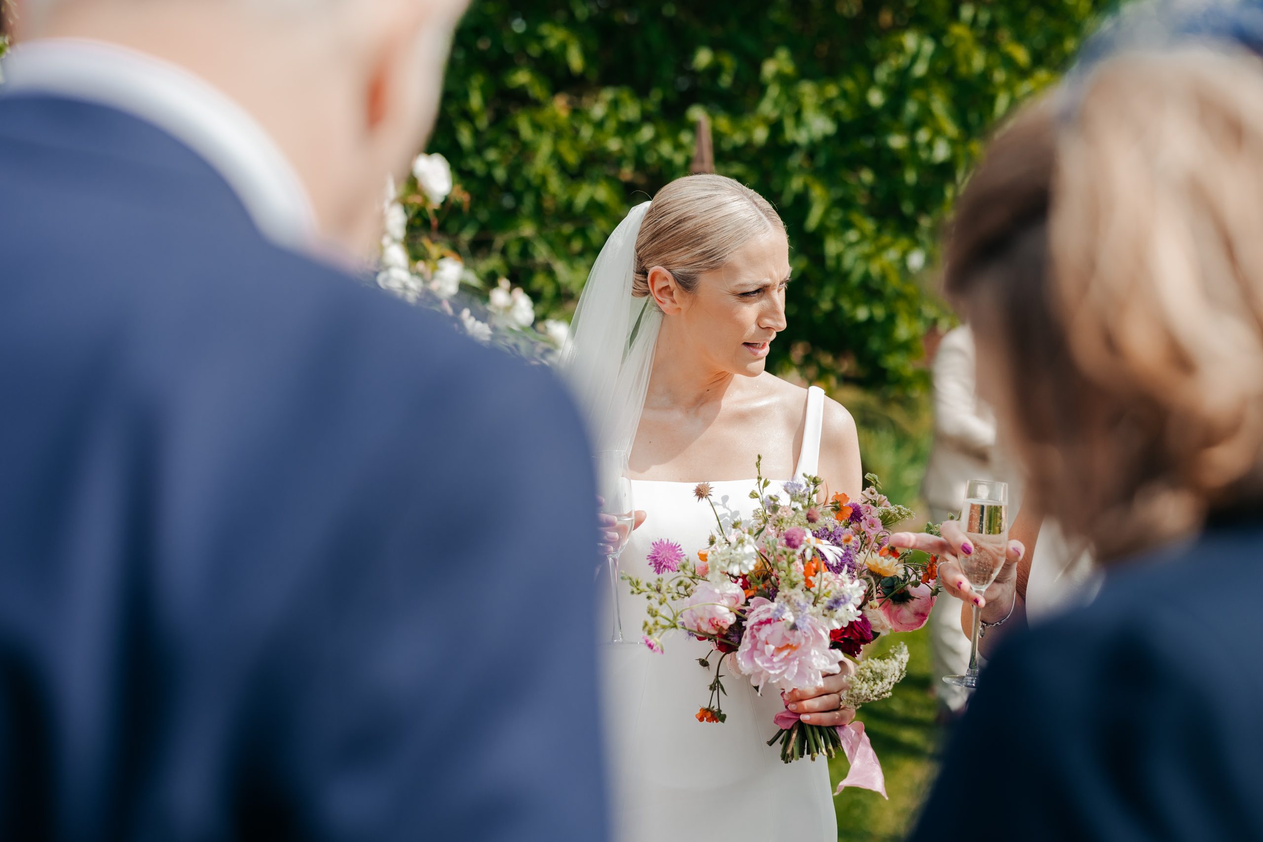 Bride and her guests enjoying a champagne reception at a marquee wedding in Suffolk, planned by UK wedding planners