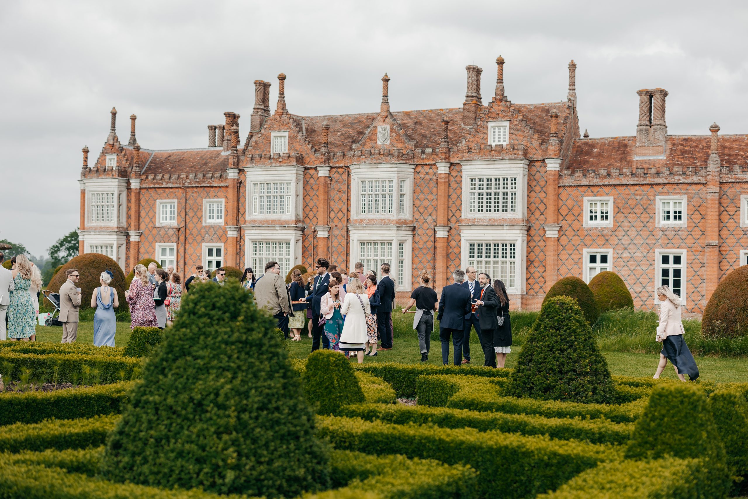 Wedding guests enjoying a champagne reception in the grounds of Helmingham Hall at a marquee wedding in Suffolk, planned by UK wedding planners