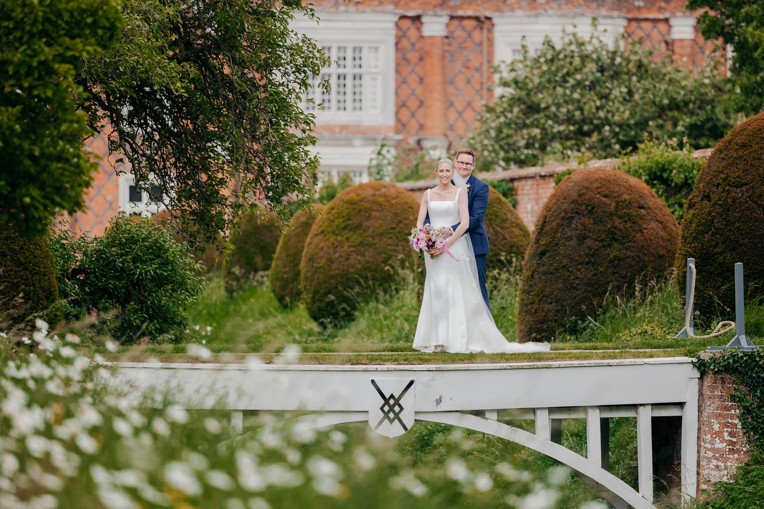 Emma & Luke sharing a moment in the grounds of Helmingham Hall, Suffolk, styled by a high-end UK wedding planner