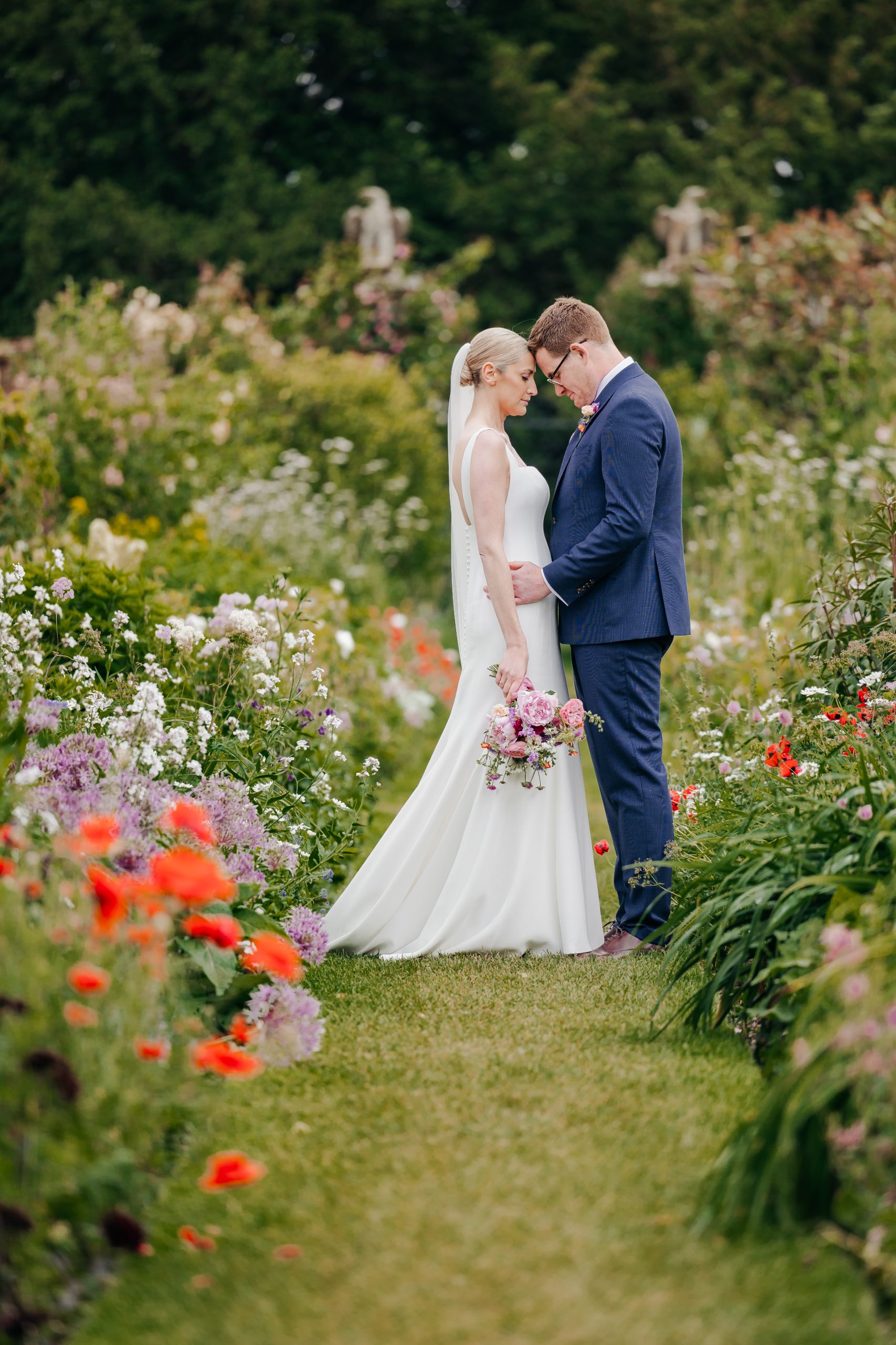 Emma & Luke sharing a moment in the grounds of country house wedding venue, Helmingham Hall, Suffolk styled by a high-end UK wedding planner