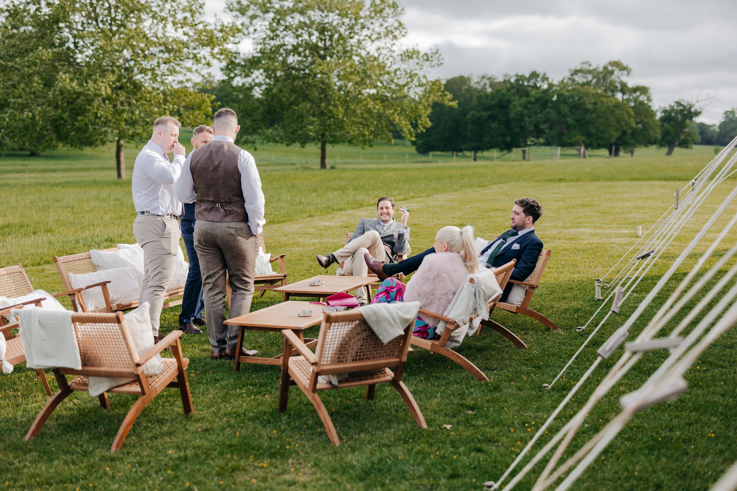 guests enjoying themselves outside a grand marquee pitched on the grounds of a stately English country house at Helmingham Hall, suffolk