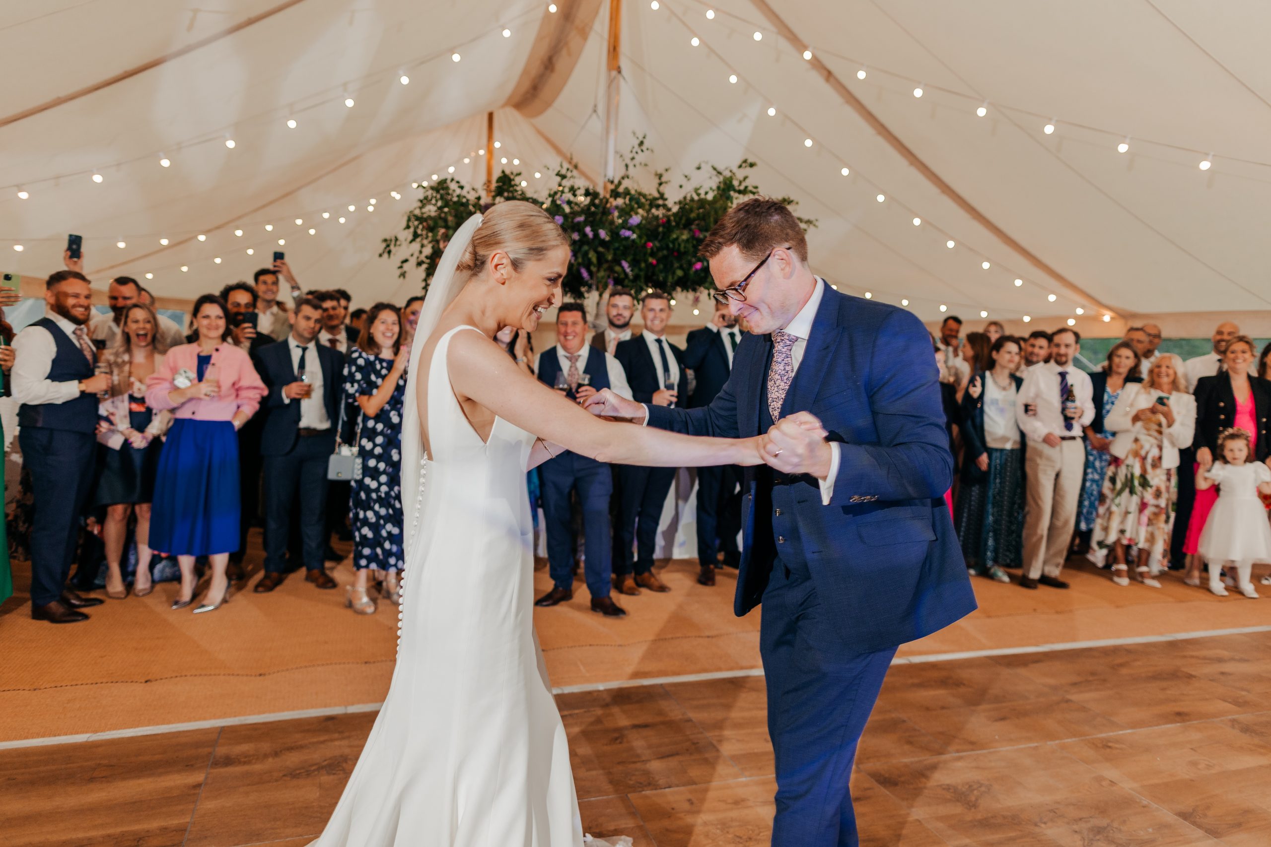 bride and groom enjoying their first dance before the evening marquee reception with flowers and fairy lights decorating the space, styled by wedding planners Hardesty Event Design