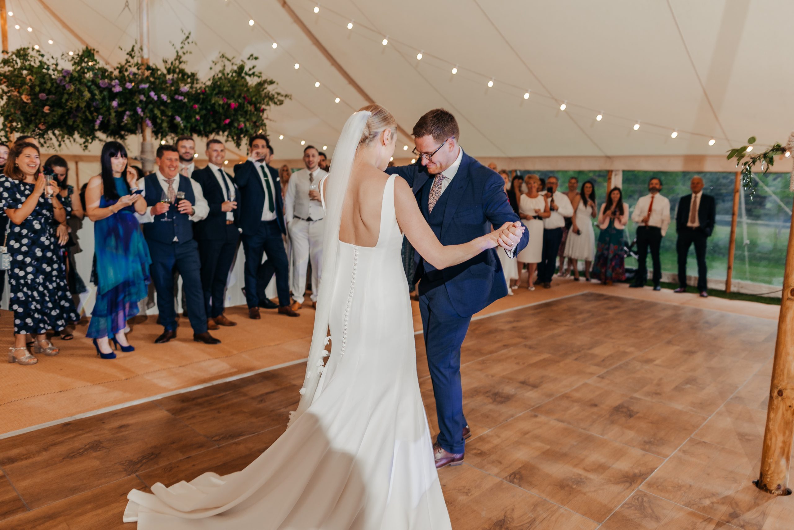 bride and groom enjoying their first dance in their marquee with flowers and fairy lights decorating the space, styled by wedding planners Hardesty Event Design