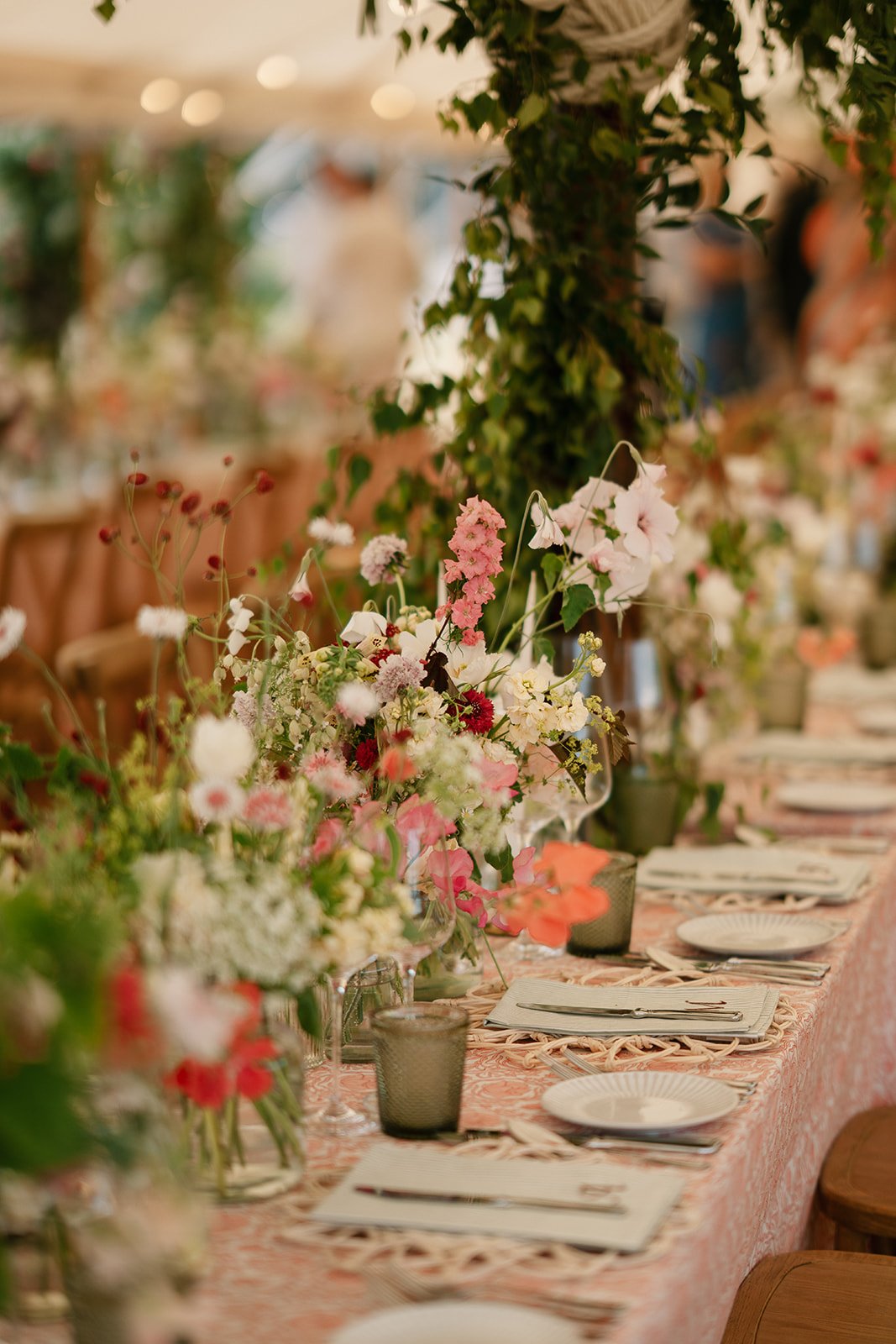 Warm and elegant tablescape with hand-printed tablecloths and abundant flowers for a luxury marquee wedding