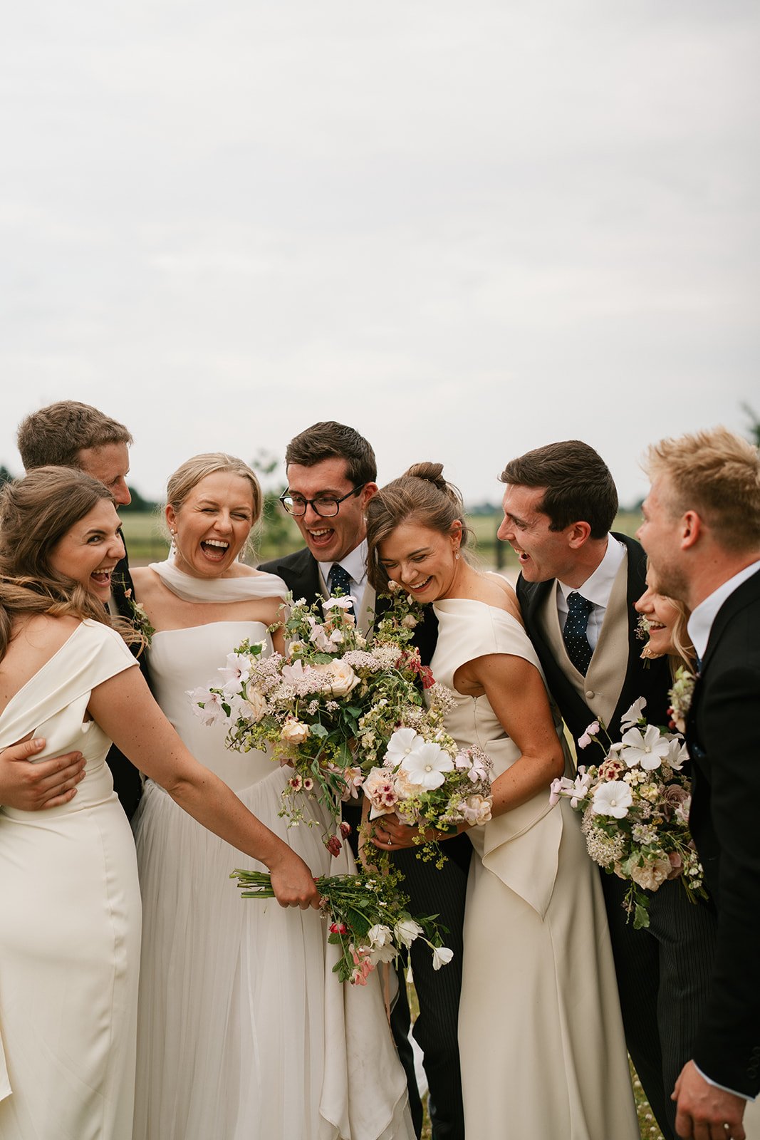 Charlotte and Ed with her bridal party elegantly captured during their marquee wedding at home planned by a luxury UK wedding planner