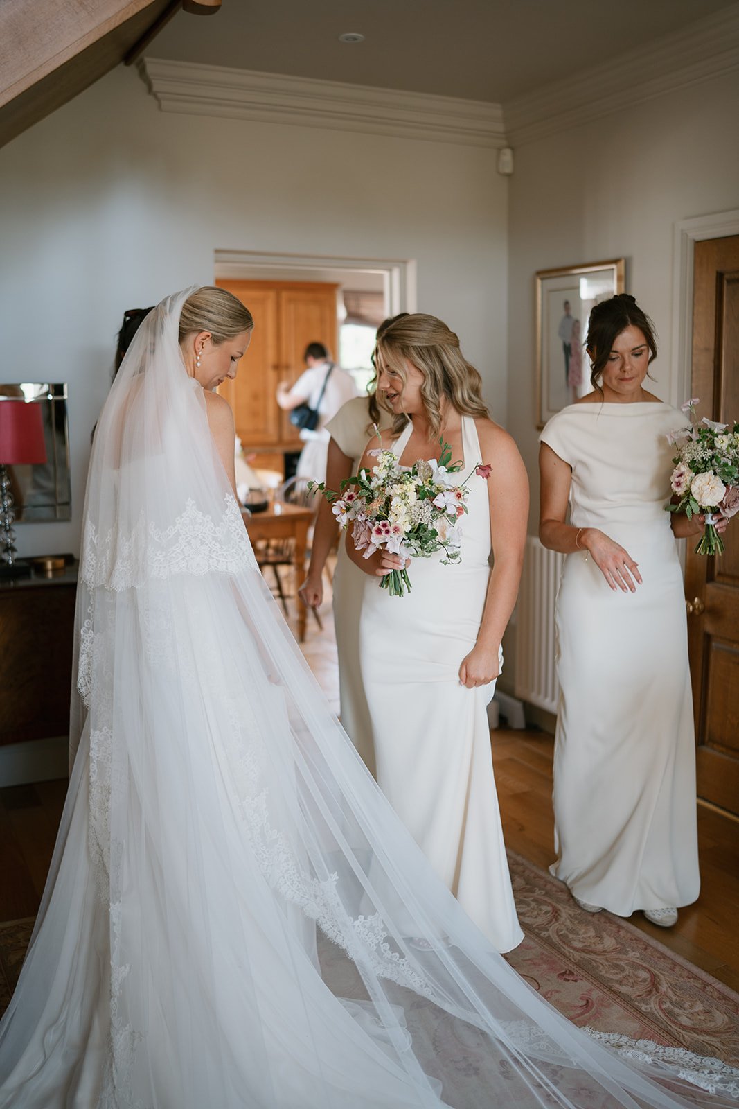 Cream, pink and coral floral arrangements with bride and bridemaids before ceremony, wedding styled by a UK luxury wedding planner