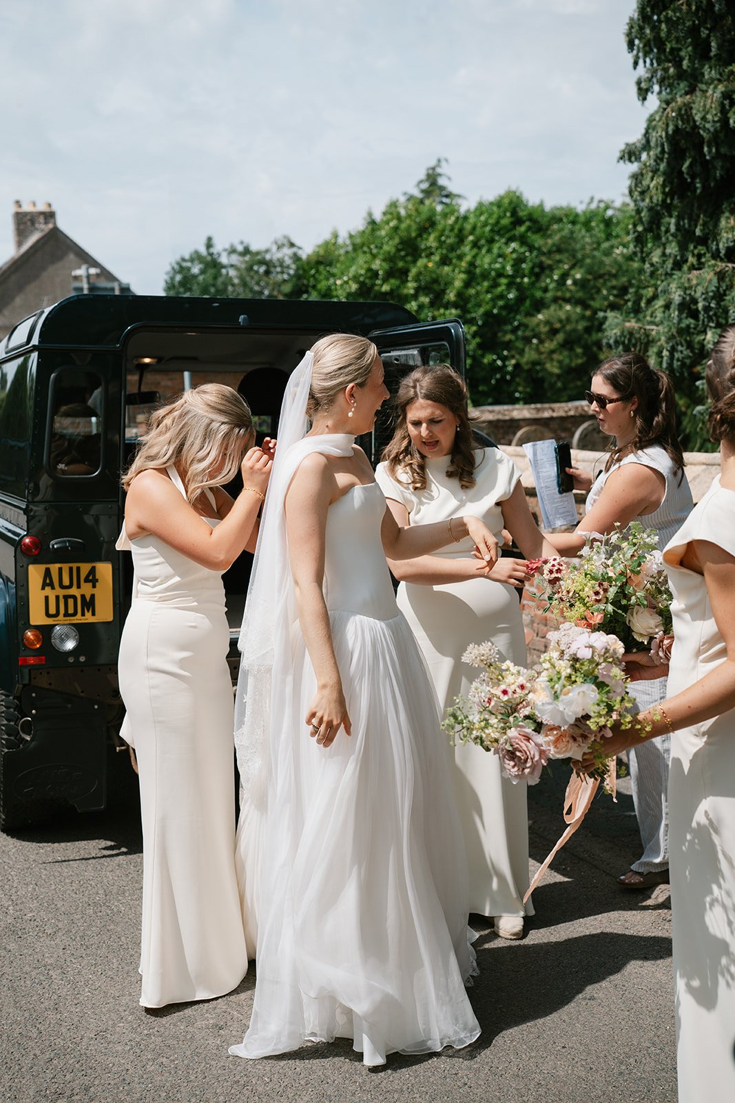 bride being helped out of wedding Land Rover by bridesmaids before church ceremony, coordinated by Hardesty Event Design