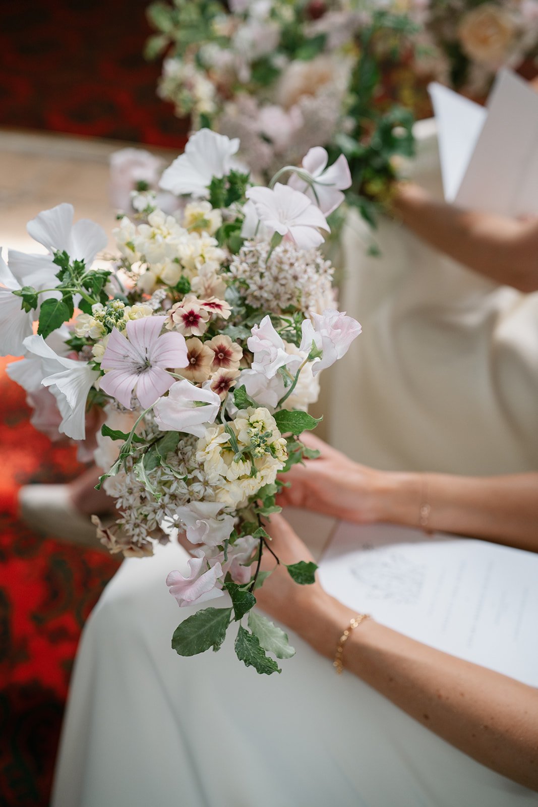 wedding bouquet of flowers filled with peaches, pinks and whites, held by the bridesmaids and styled by UK wedding planner Hardesty Event Design