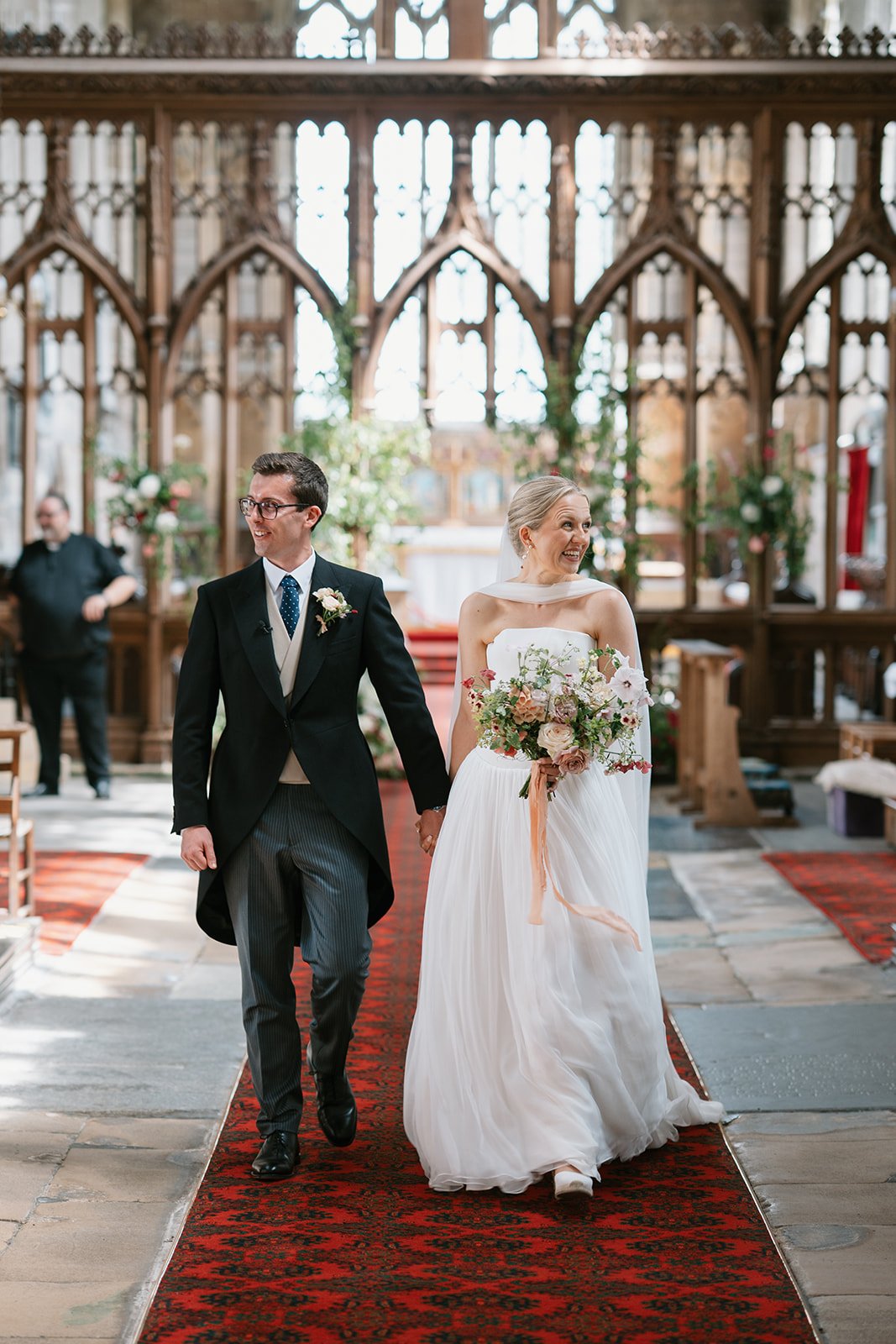 Bride and groom leaving their church smiling at a high-end country house wedding in Norfolk planned by a luxury UK wedding planner