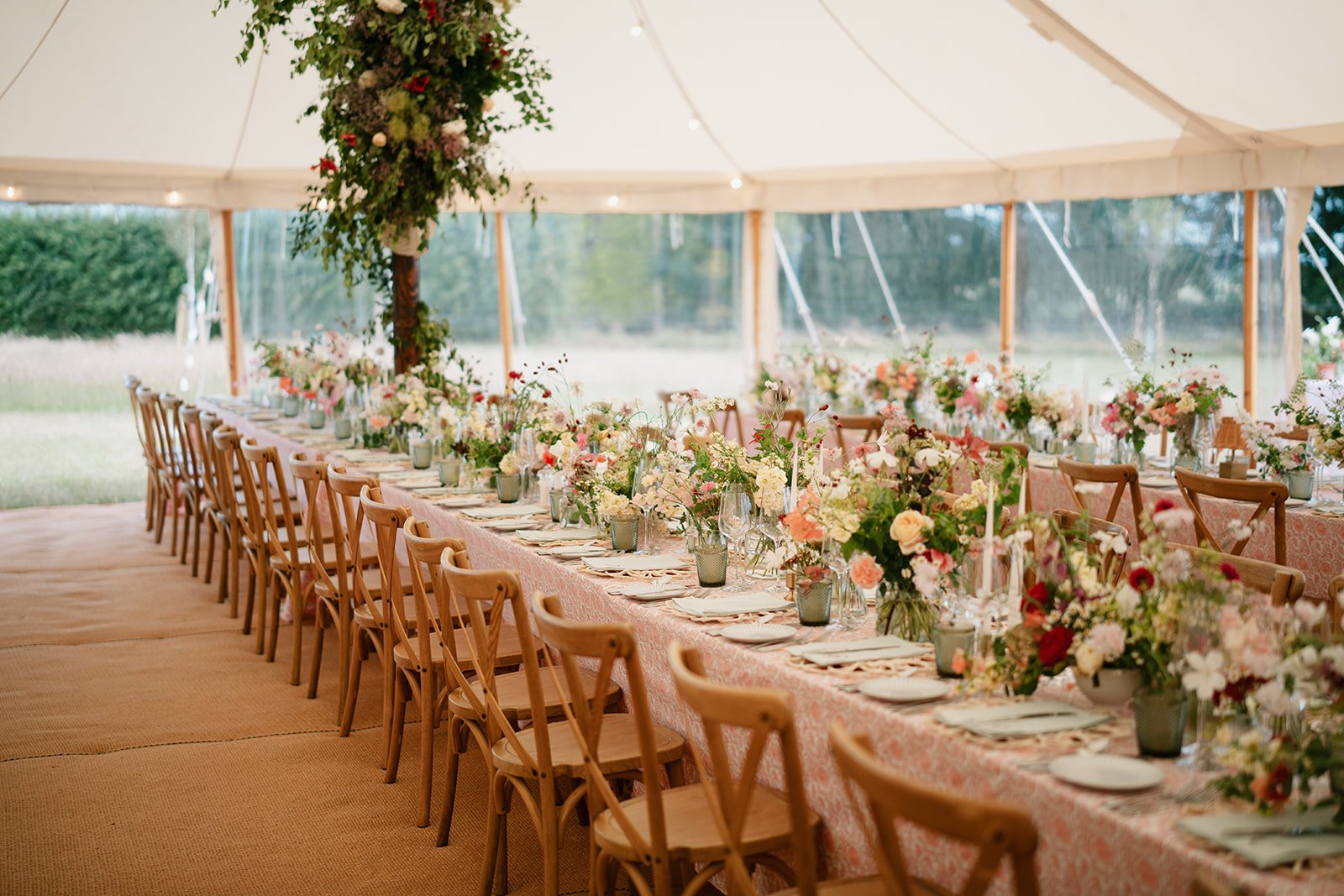 Warm and elegant tablescape with hand-printed tablecloths and abundant flowers for a luxury marquee wedding