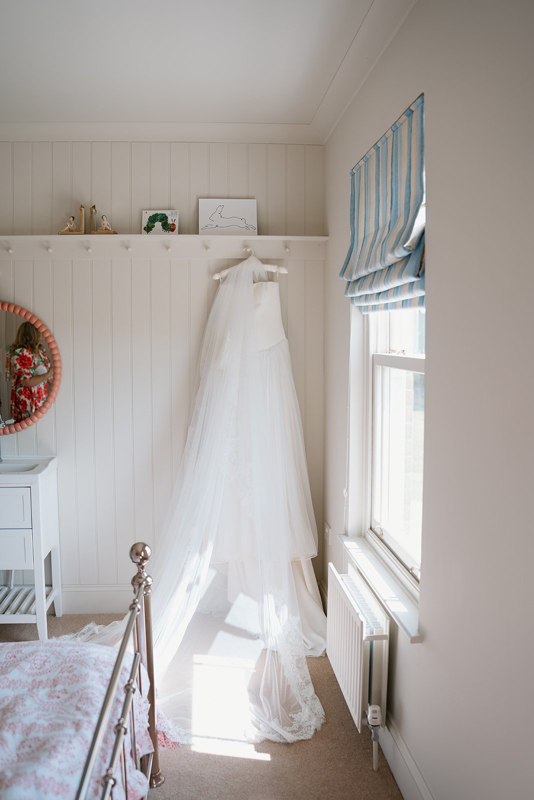 Emma Beaumont bridal gown hung in the bedroom of the bride for her at home marquee wedding planned by uk wedding planner Hardesty Event Design