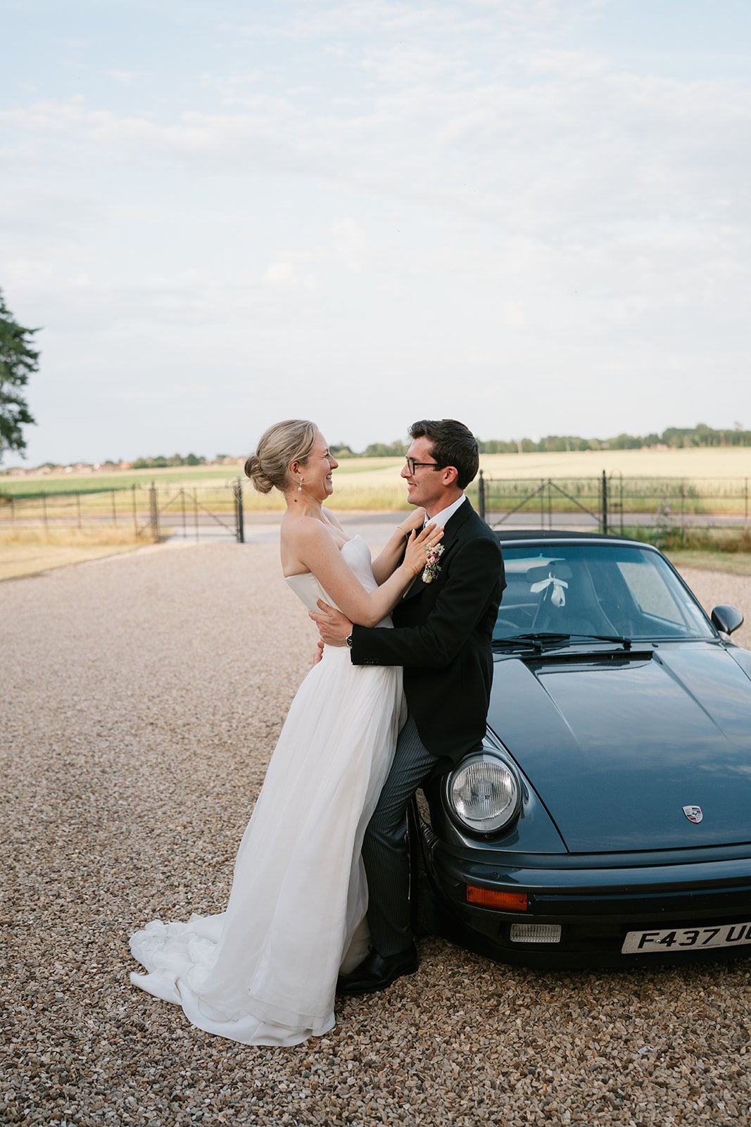 Charlotte and Ed, elegantly captured with their wedding car during their marquee wedding at home planned by a luxury UK wedding planner