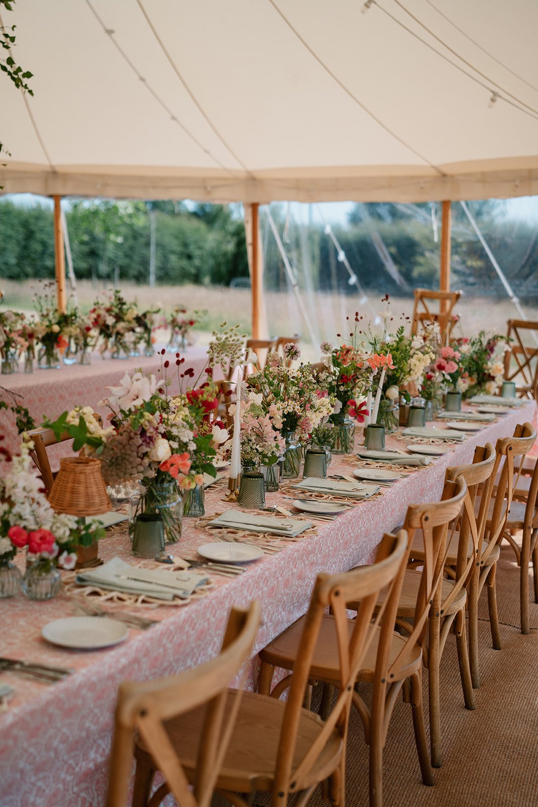Soft abundant flowers in shades of cream, coral and red, arranged along the length of a marquee table